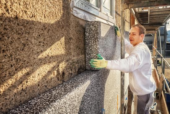 Energetische Sanierung Kosten: Handwerker dämmt Fassade