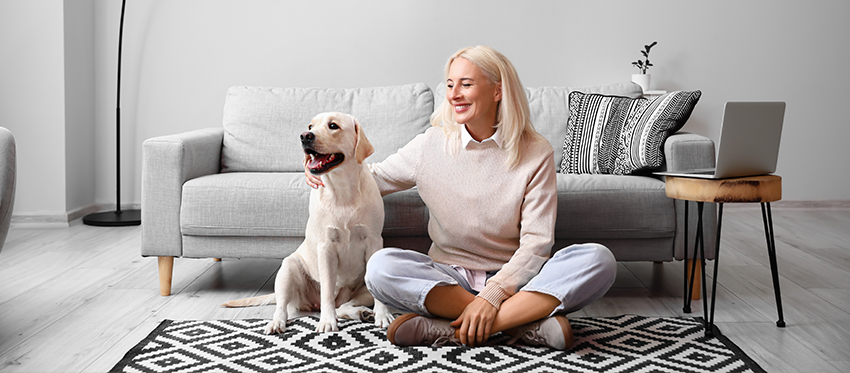 Frau und Hund sitzen vor Sofa