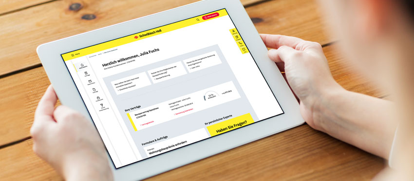 Person hält Tablet auf Tischplatte