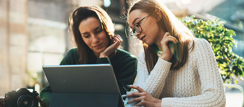 Zwei Frauen sitzen am Tisch vor einem Laptop