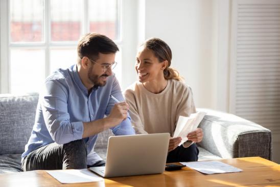 Frau und Mann sitzen auf Sofa vor dem Laptop