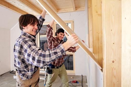 Zwei Handwerker beim Innenausbau bringen Wandplatte an