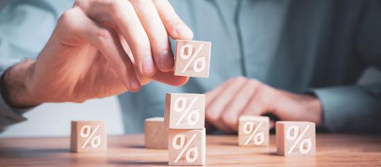Effektiver Jahreszins: Mann stapelt kleine Bausteine mit Prozent-Symbolen