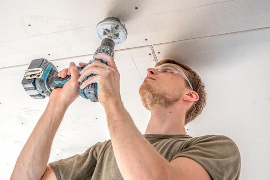 Mann bohrt Löcher in Decke für LED-Deckenspots