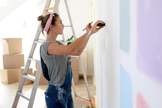 Frau bereitet Zimmerwand für Farbanstrich vor