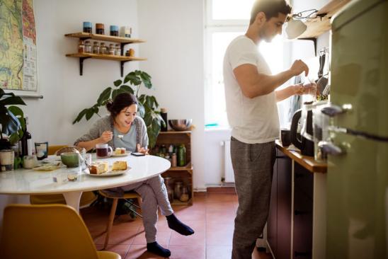 Geld anlegen als Student: Junger Mann und junge Frau in einer Wohnküche