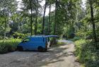 Blauer Camper steht auf einem Parkplatz im Wald