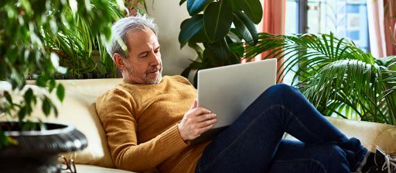 Bausparvertrag teilen: Mann auf Sofa schaut auf den Laptop