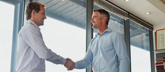 Shot of two businessmen shaking hands while standing in an office