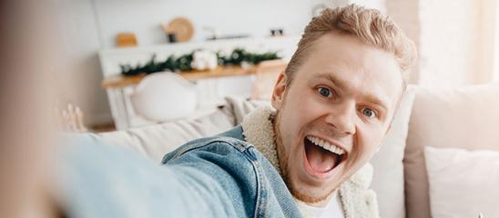 Bausparen für junge Leute Lachender junger Mann macht ein Selfie