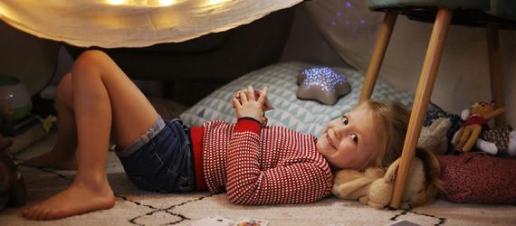 Kind liegt in selbstgebauter Höhle unter dem Tisch