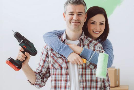 Bausparen für Modernisierer: Paar mit Bohrmaschine und Farbrolle in der Hand Paar mit Bohrmaschine und Farbrolle in der Hand