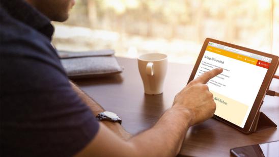 Mann tippt auf Tablet am Schreibtisch