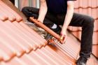 Dachdecker bringt neue Dachziegel an