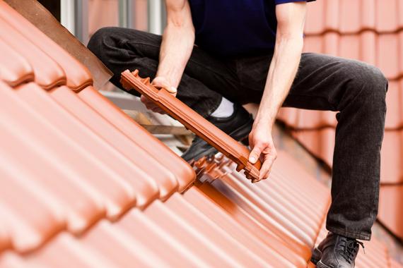 Dachdecker bringt neue Dachziegel an