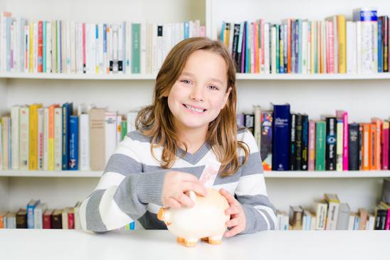 Kind steckt 10-Euro-Schein in ein Sparschwein