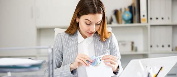 Cash Stuffing: Junge Frau legt Geld in einen Briefumschlag