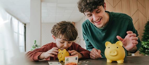 Vater und Sohn stecken Geld in Sparschweine 