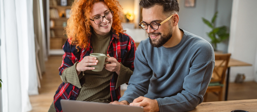 Mann und Frau sitzen gut gelaunt vor einem Laptop