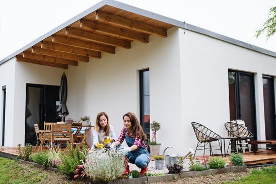 Zwei Frauen bepflanzen Grünstreifen an Hausterrasse