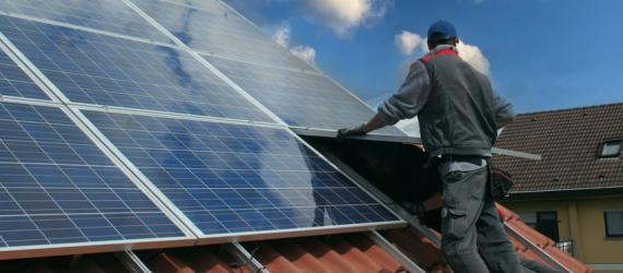 Handwerker installiert Solarkollektor aufs Hausdach