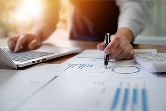 Ergänzungskredit: Person rechnet mit Tabellen und Laptop