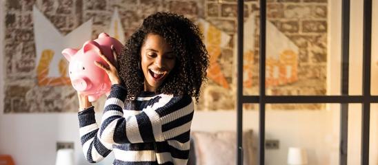 Junge Frau hält Sparschwein in der Hand.