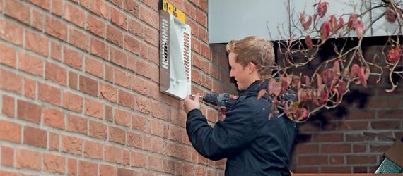 Mann installiert Lüftungsanlage von außen