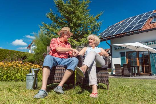 Erbschaftsteuer Immobilien: Älteres Paar sitzt im Garten vor dem Haus