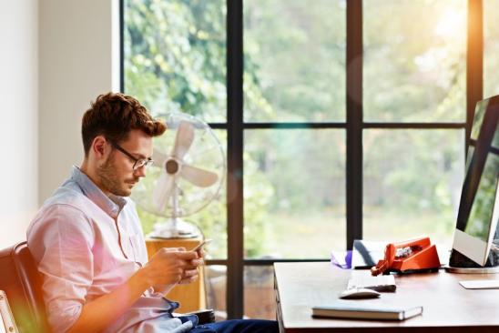 Shot of a young man sending at text message while sitting in his home office
