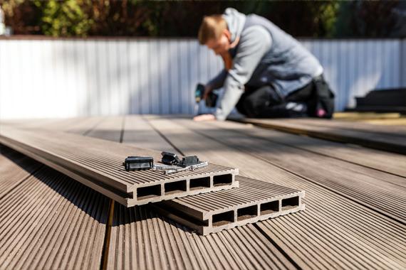 Mann verlegt WPC-Dielen auf der Terrasse