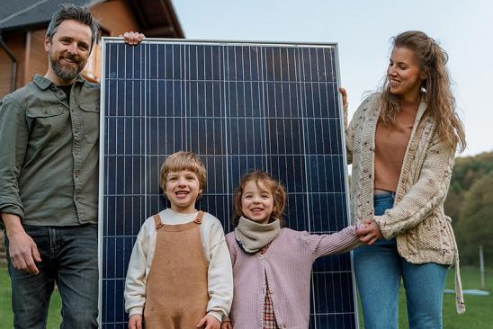 Familie mit Solarmodul vor ihrem Haus.