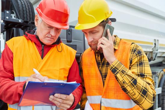Bauleiter und Vorarbeiter mit Checkliste und Smartphone