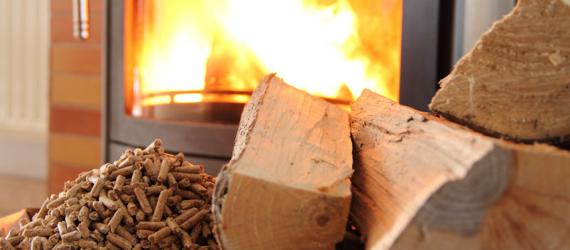 Heizen mit Holz: Holzscheite und Pellets vor Kaminofen