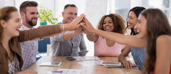 Baugemeinschaft: Menschen um einen Tisch herum machen High Five