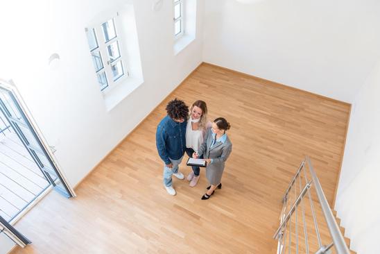 Junges Paar mit Immobilienmaklerin bei Besichtigung einer Eigentumswohnung