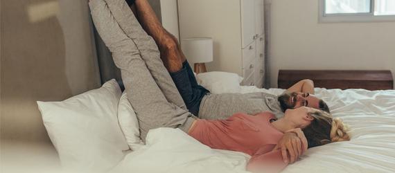 Wohnung kaufen oder mieten: Paar liegt entspannt auf dem Bett