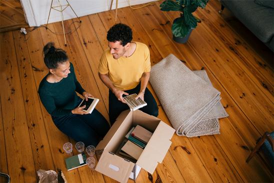 Wohnung kaufen oder mieten: Paar packt Umzugskarton aus