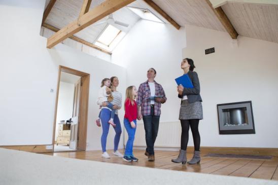 Family being shown a new home by an estate agent holding a clipboard and paperwork. Shot from below.