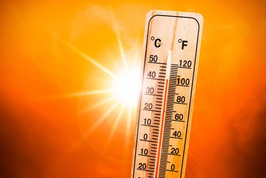 Thermometer vor orangefarbenem Himmel mit Sonne