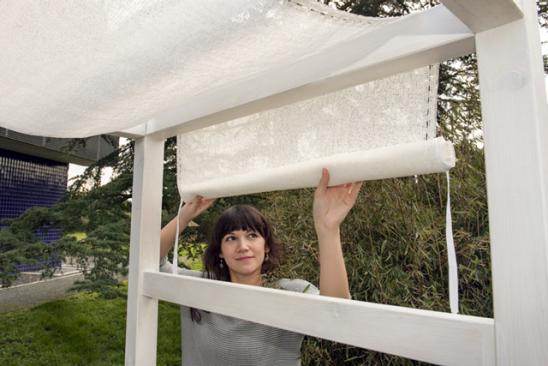 Frau zieht Vorhang über Gartenlounge