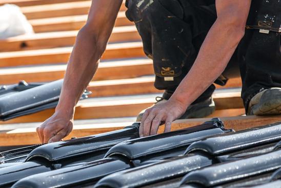 Handwerker verlegt Dachziegel