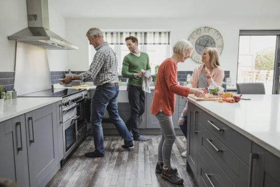Jüngeres Paar hilft älterem Paar in der Küche