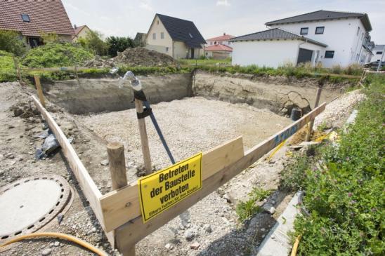 construction pit for foundation of residential house with sign in german language: keep off construction site - Parents are liable for their children