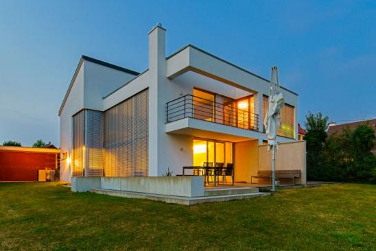 Modern Architecture House with large window front and closed aluminium shutters illuminated at twilight under blue cloudless summer sky. Made with Sony A7RII - full owner property released.