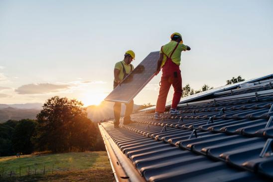 Arbeiter installieren PV-Anlage auf einem Hausdach