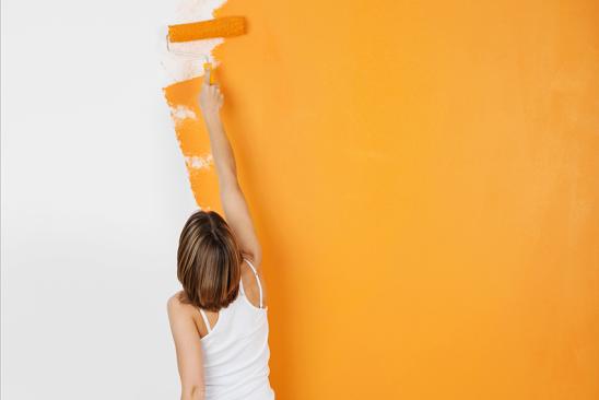 Frau streicht Wand orange.