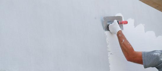 Sanierung Fassade: Mann verputzt Außenwand