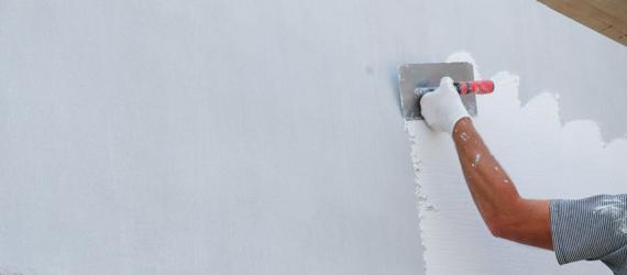 Sanierung Fassade: Mann verputzt Außenwand