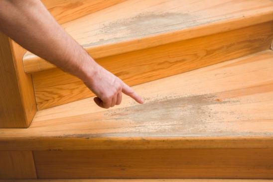 Hand eines Mannes zeigt auf stark abgenutzte Treppenstufe